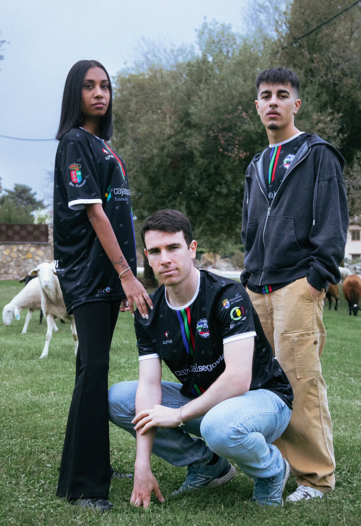 Tres modelos con la equipación en un prado con ovejas